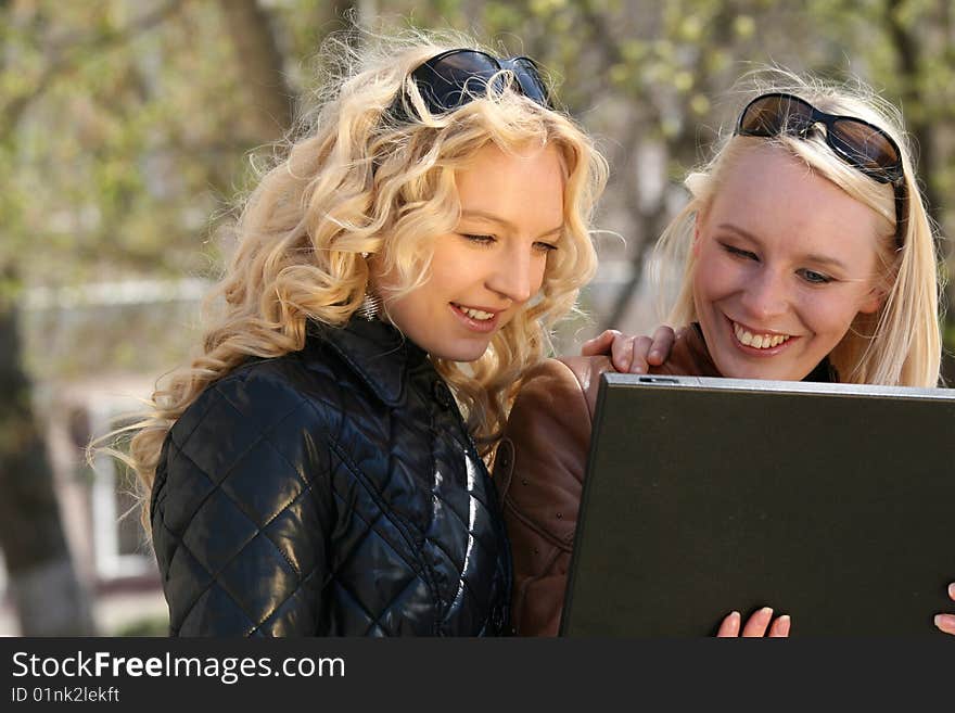 Two women with laptop in the city park. Two women with laptop in the city park