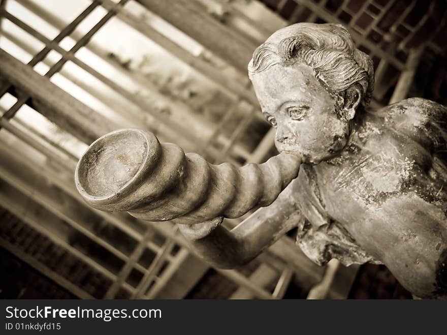Cupid blowing horn.Aged photo style.Shallow depth of field with focus on the closest part of the horn.