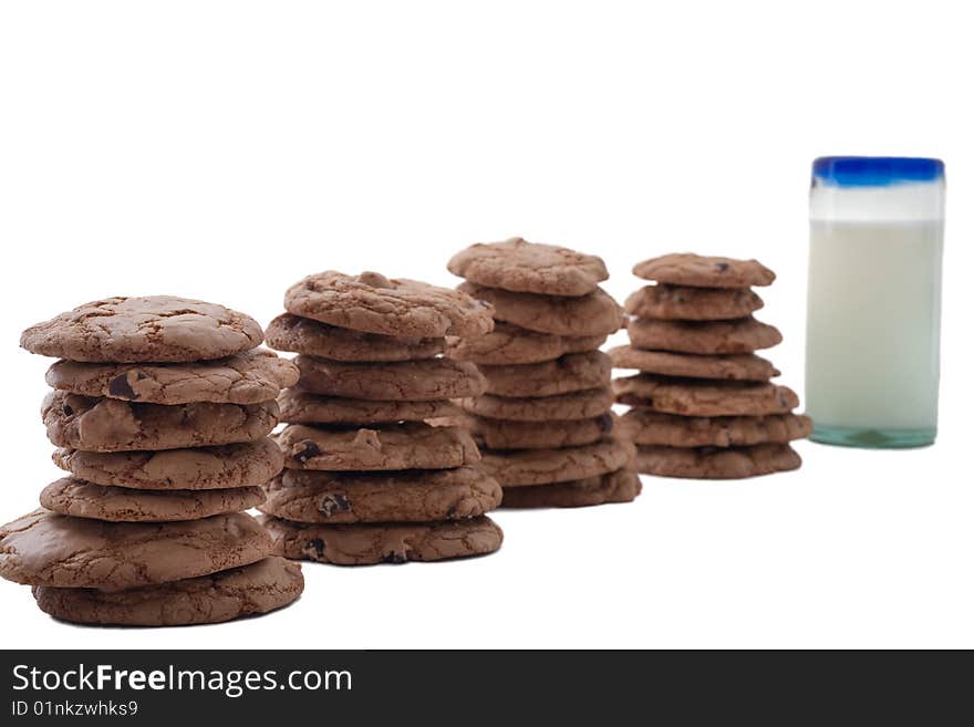 Stacks of chocolate chip cookies arranged in a row, ending in glass of milk. Stacks of chocolate chip cookies arranged in a row, ending in glass of milk.