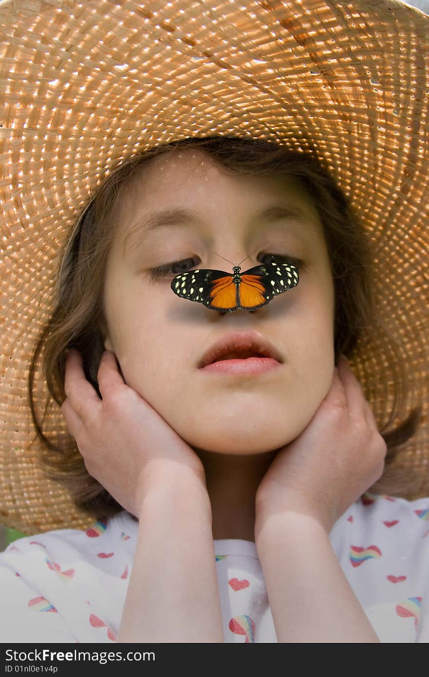 A child in a straw hat with a butterfly on her nose. A child in a straw hat with a butterfly on her nose