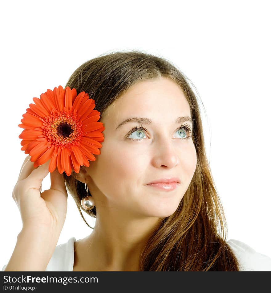 A smiling beautiful young woman in a white dress with a bright red flower near her face. A smiling beautiful young woman in a white dress with a bright red flower near her face