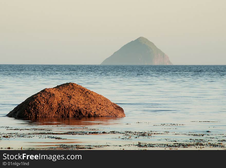 Ailsa Craig Island with rock in the sea in fore ground