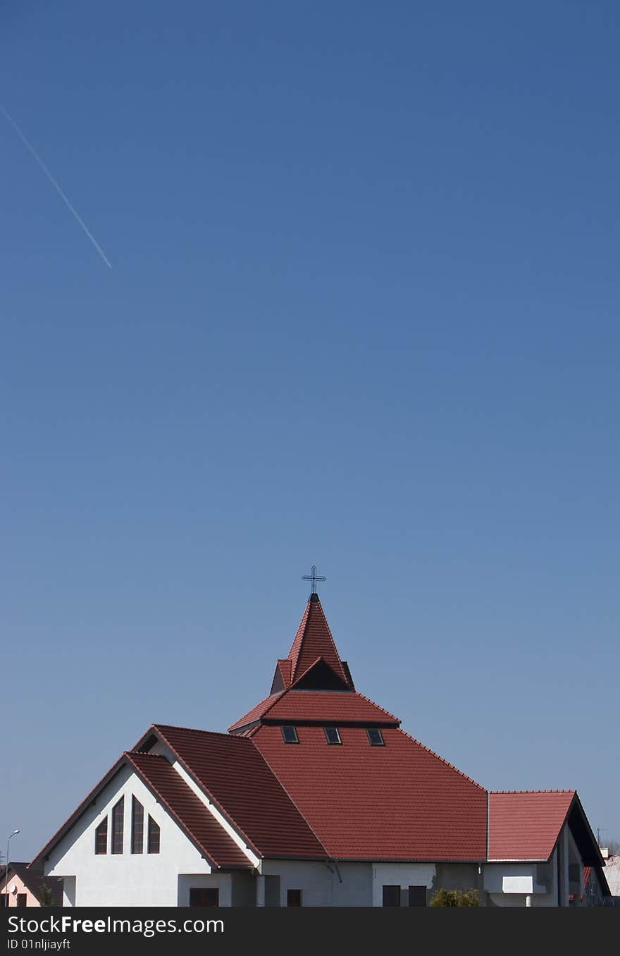 The red roof of a modern church against blue sky. The red roof of a modern church against blue sky.