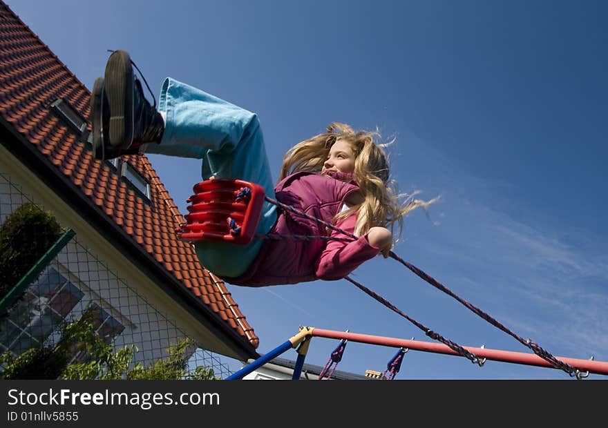 Young girl on a swing in the backyard. Young girl on a swing in the backyard.