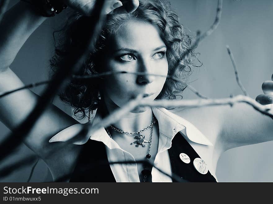 Portrait of a young beautiful girl in black and white with branches in the foreground. Portrait of a young beautiful girl in black and white with branches in the foreground