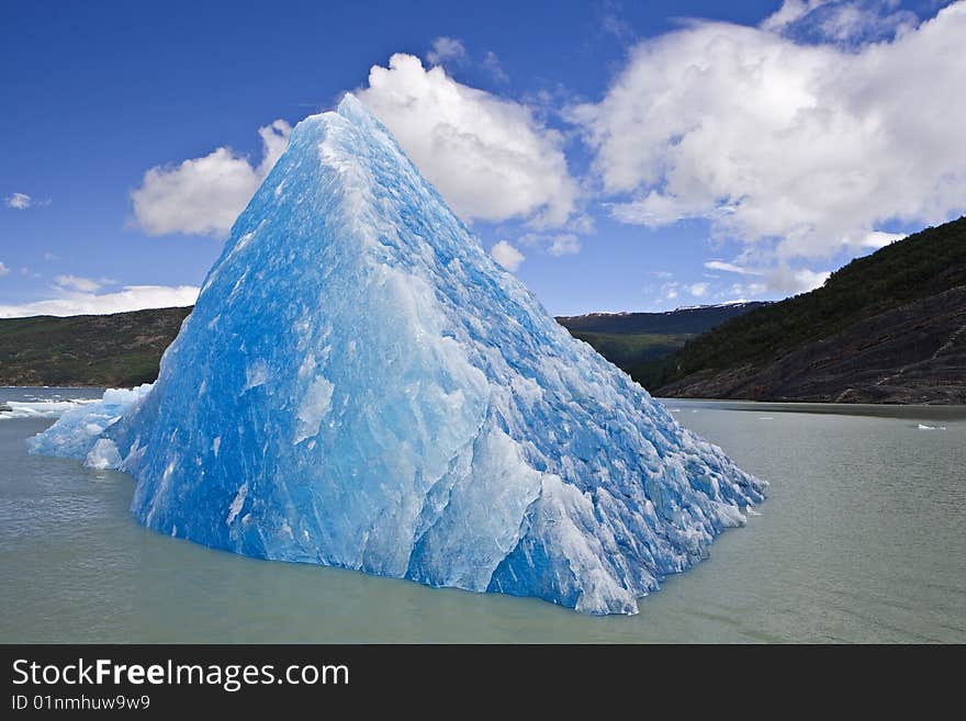 Blue, emerald Iceberg in floating gray water. Blue, emerald Iceberg in floating gray water