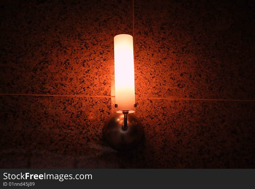 Glowing orange lamp on a tile wall