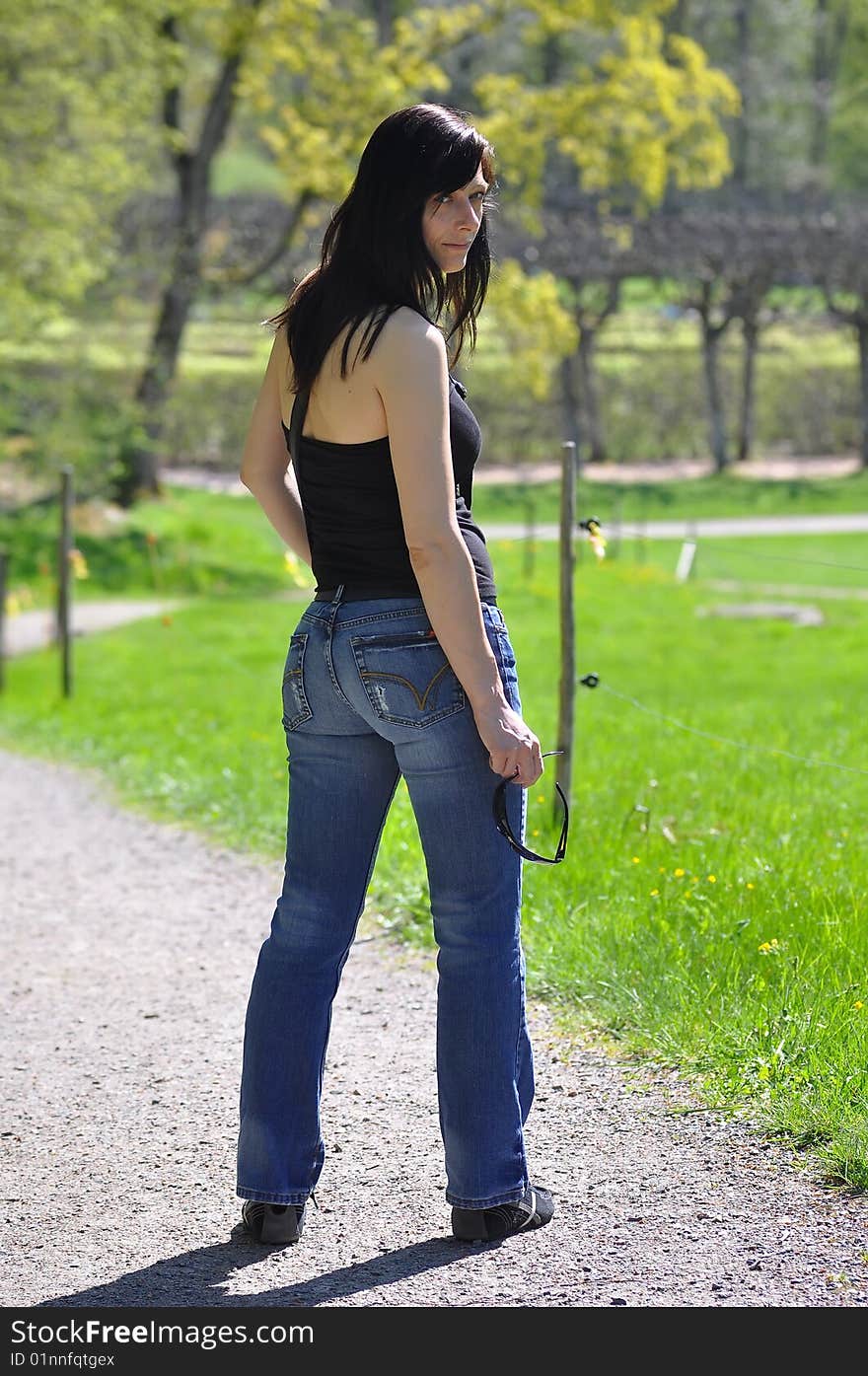 Woman standing in green park looking back. Woman standing in green park looking back