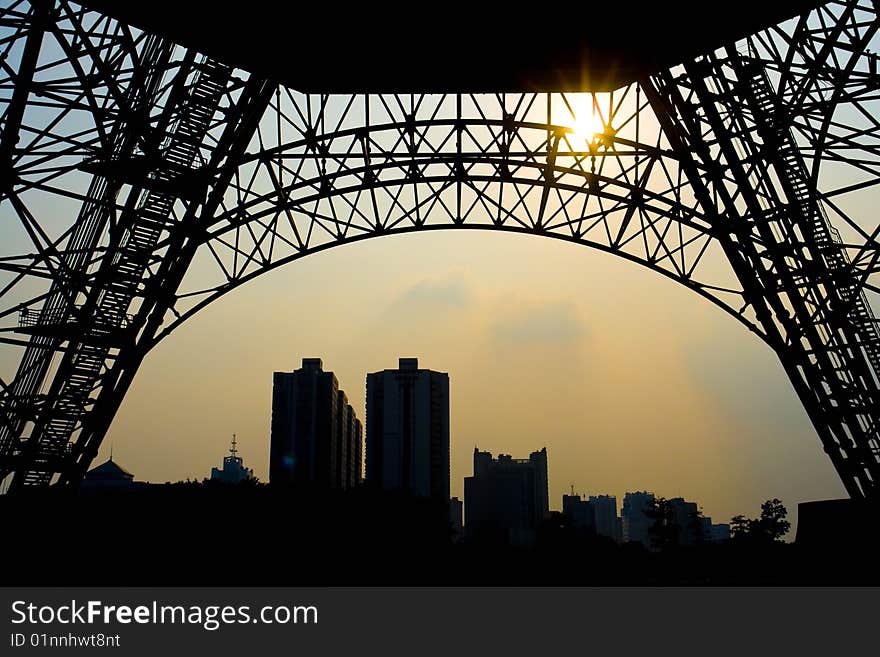 A city under sunset view through a TV tower base. A city under sunset view through a TV tower base