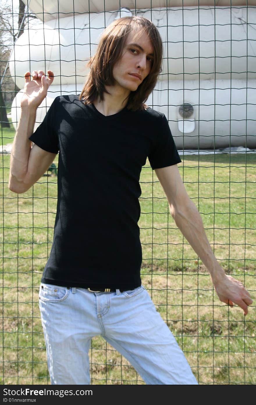 Flirting man standing in front of a wire fence