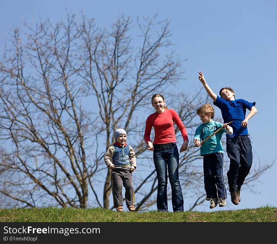 Four children jump on the green field.