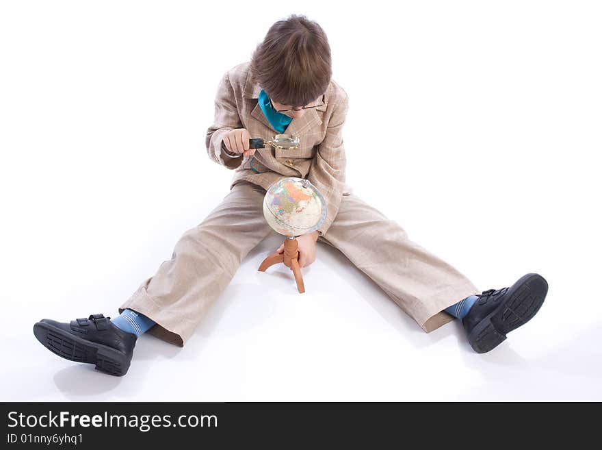 The boy of 6-years considers the globe through magnifying glass. The boy of 6-years considers the globe through magnifying glass