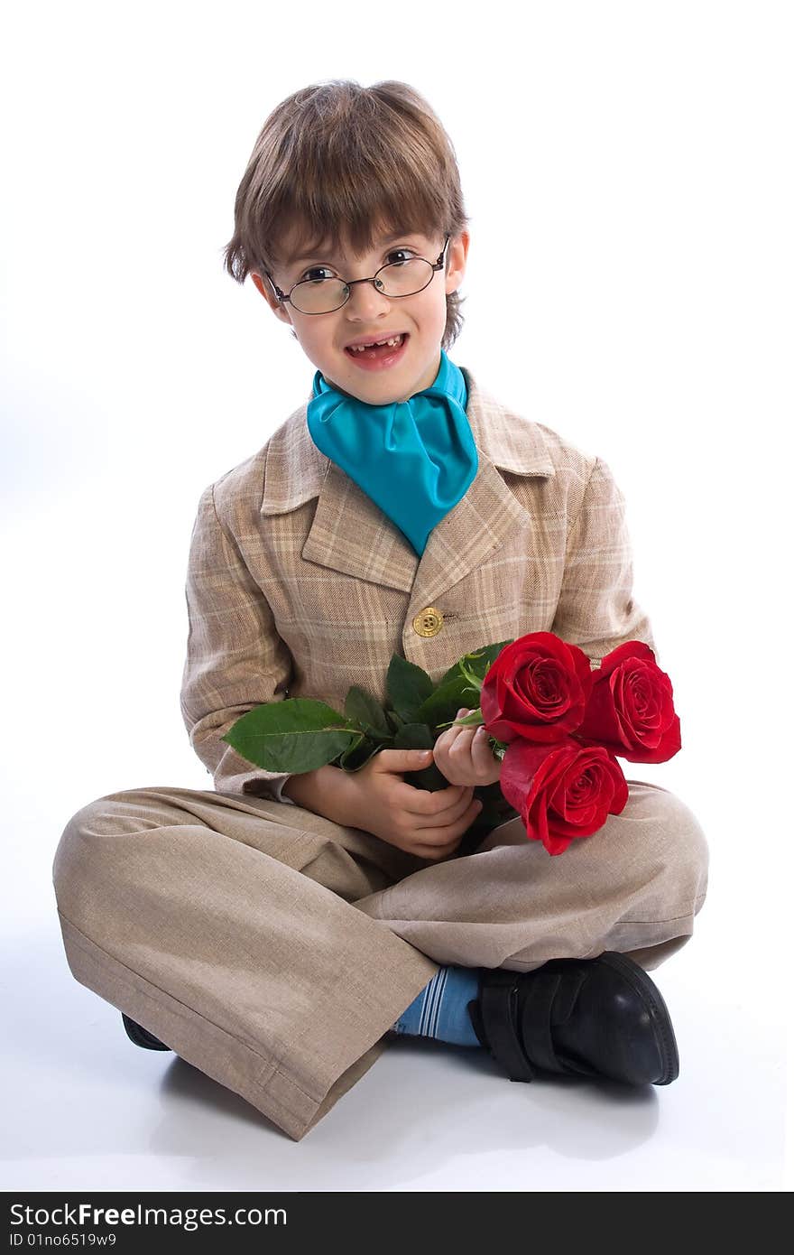 The boy of 7-years sits with a bouquet of roses looks in the chamber on the white isolated background. The boy of 7-years sits with a bouquet of roses looks in the chamber on the white isolated background