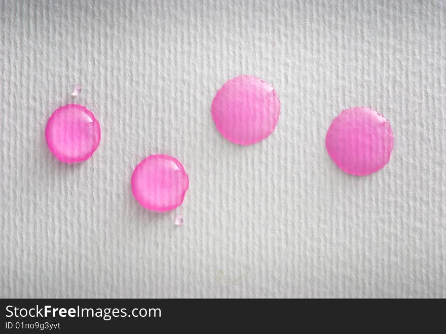 Four pink water drops on white paper