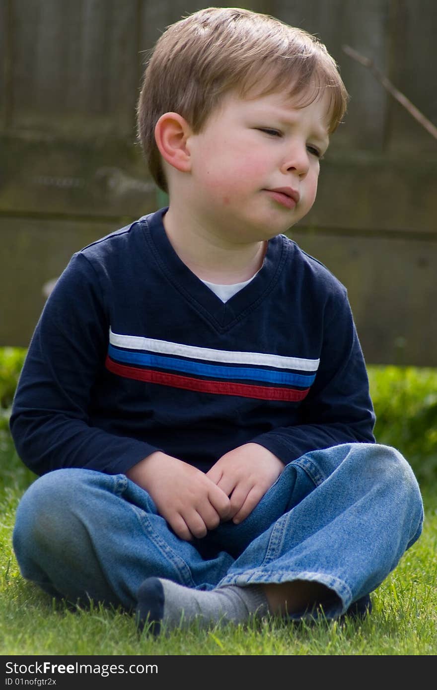 A young boy sulking after a row with his friends. A young boy sulking after a row with his friends