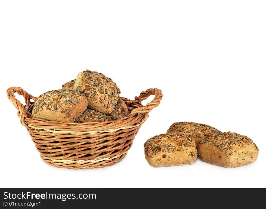 Fresh baked multi grain rolls in a wicker basket with three rolls to one side, over white backgound. Fresh baked multi grain rolls in a wicker basket with three rolls to one side, over white backgound.