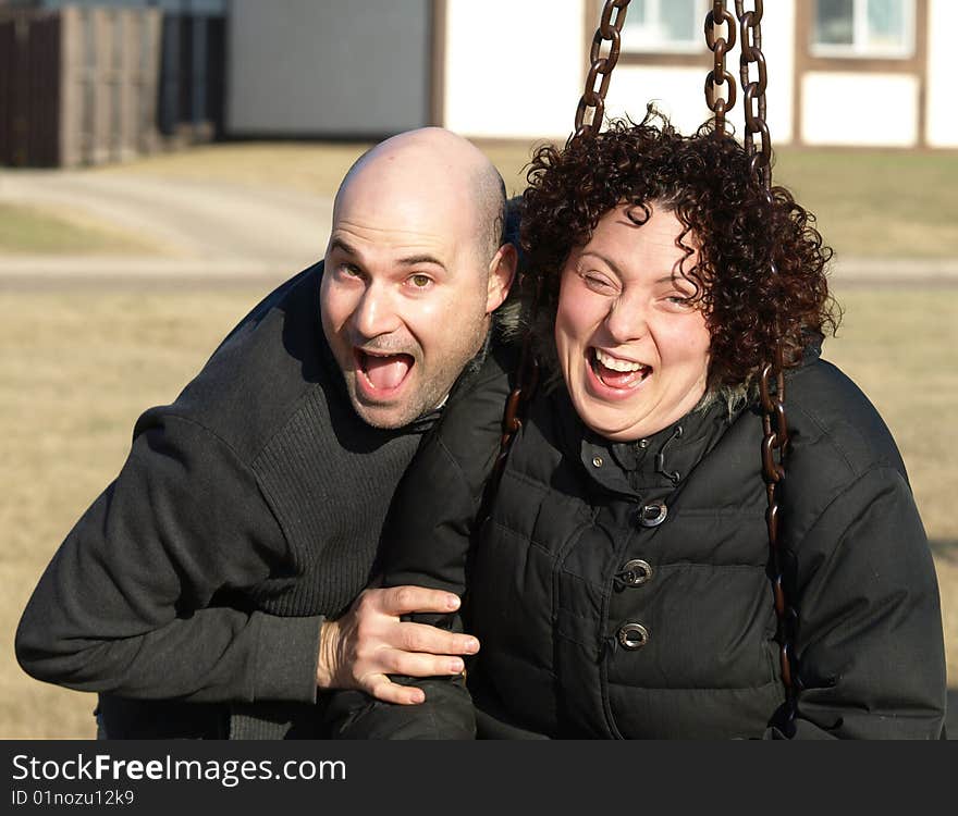 Young couple with funny expressions having fun on a swing outdoors. Young couple with funny expressions having fun on a swing outdoors.