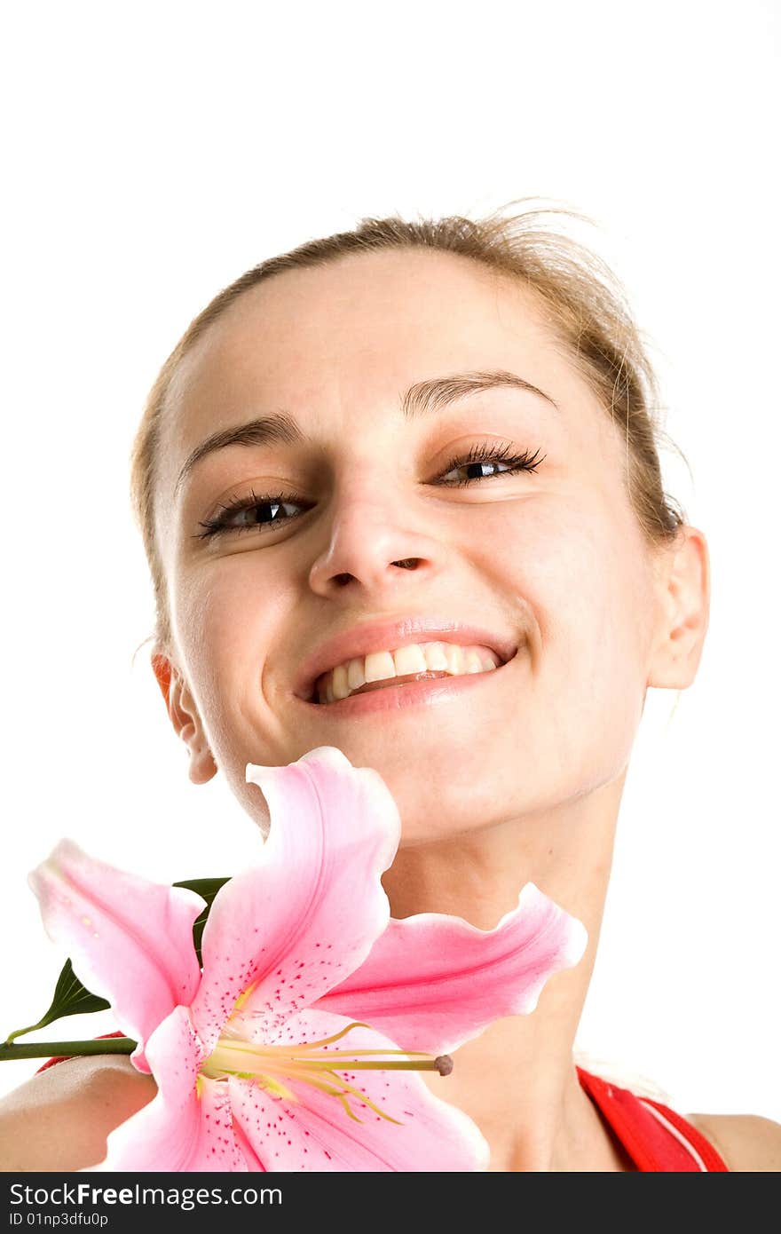 A portrait of a smiling nice blond girl with a pink lily near her face on a white background. A portrait of a smiling nice blond girl with a pink lily near her face on a white background