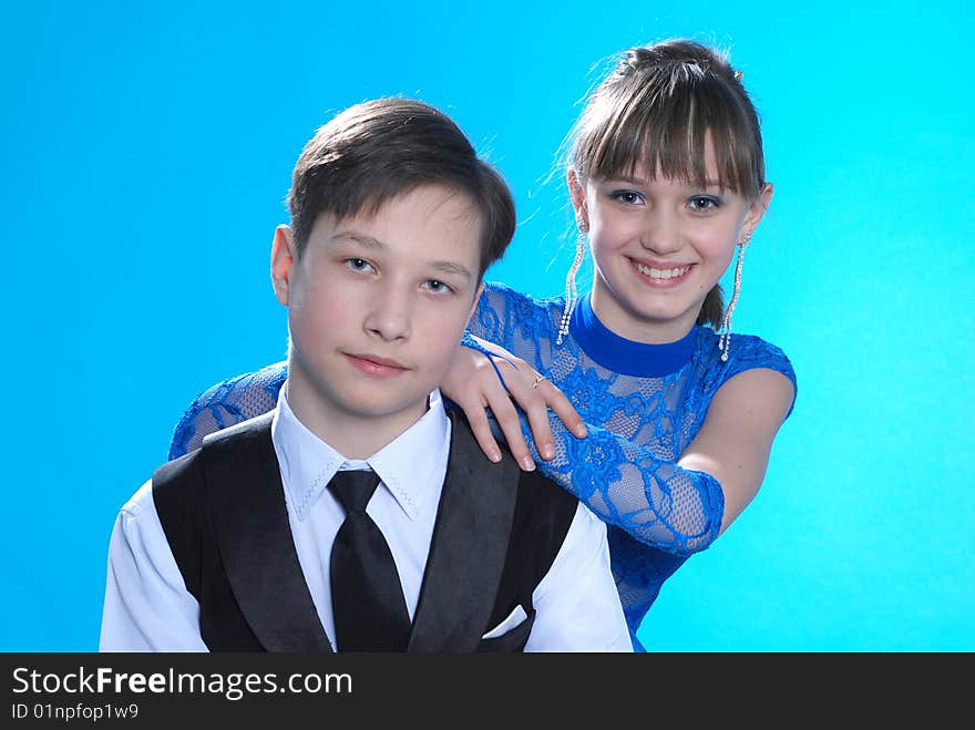 Boy and girl posing in studio on blue background