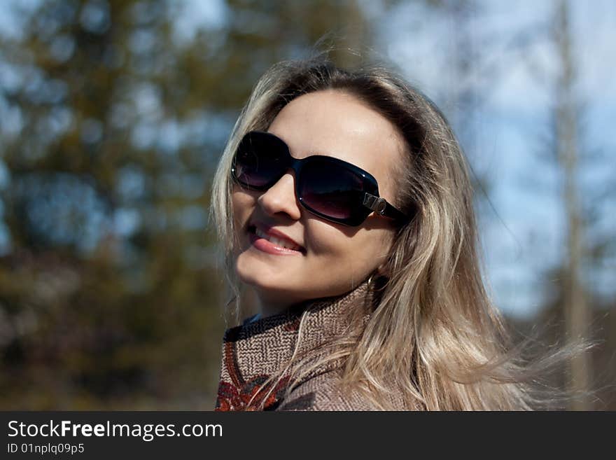 Beautiful smiling girl on background coniferous wood and blue sky