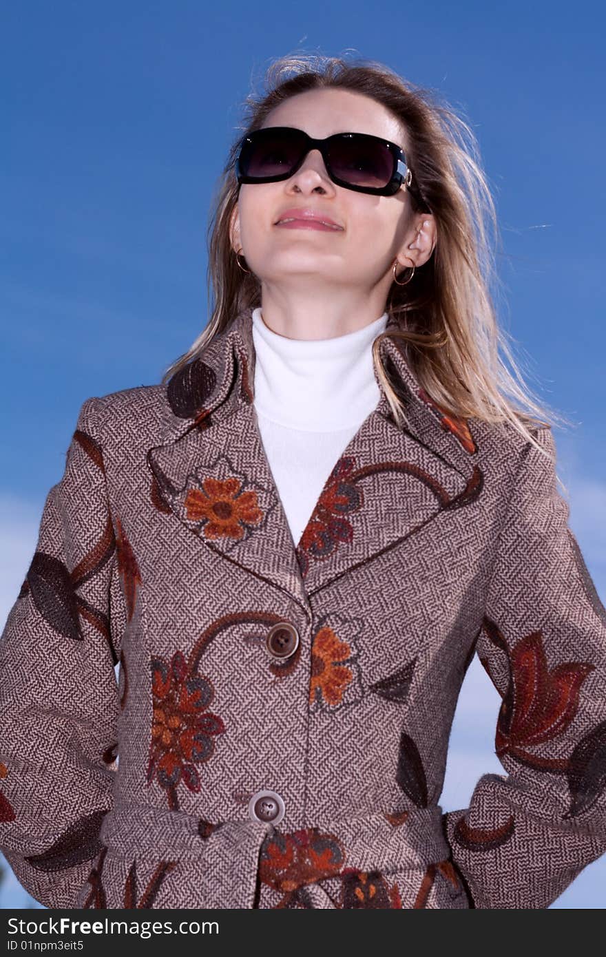 Pretty woman on background blue sky in sun-protective spectacles