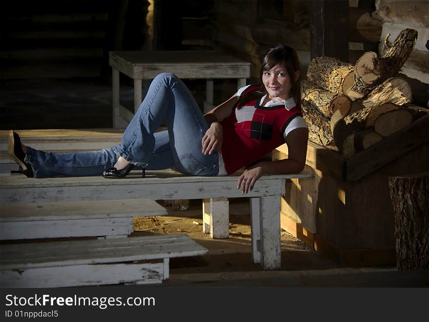 A teen girl kicks back on an old bench in a rustic log cabin. A teen girl kicks back on an old bench in a rustic log cabin.