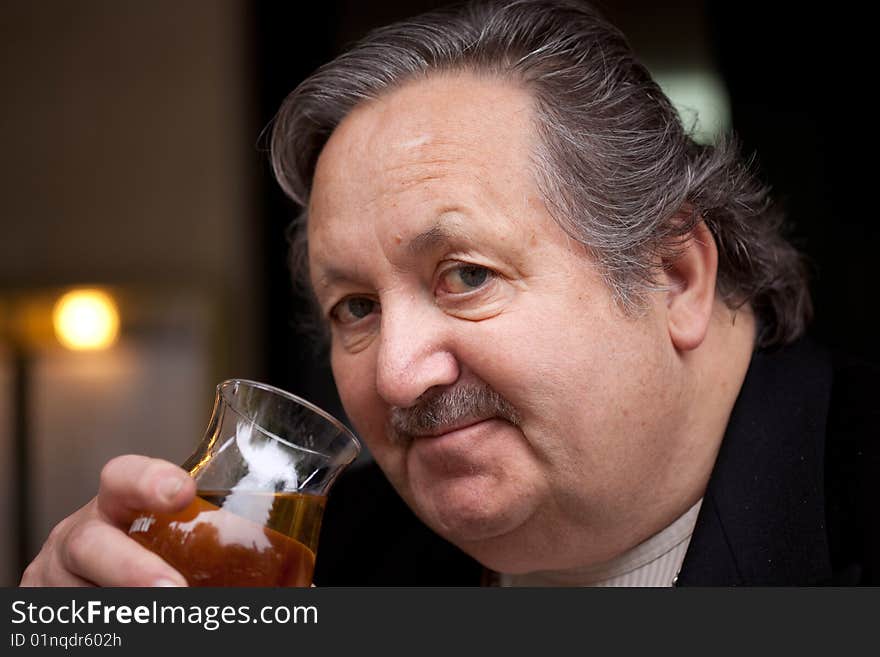 An old man with glass wine in restaurant. An old man with glass wine in restaurant.