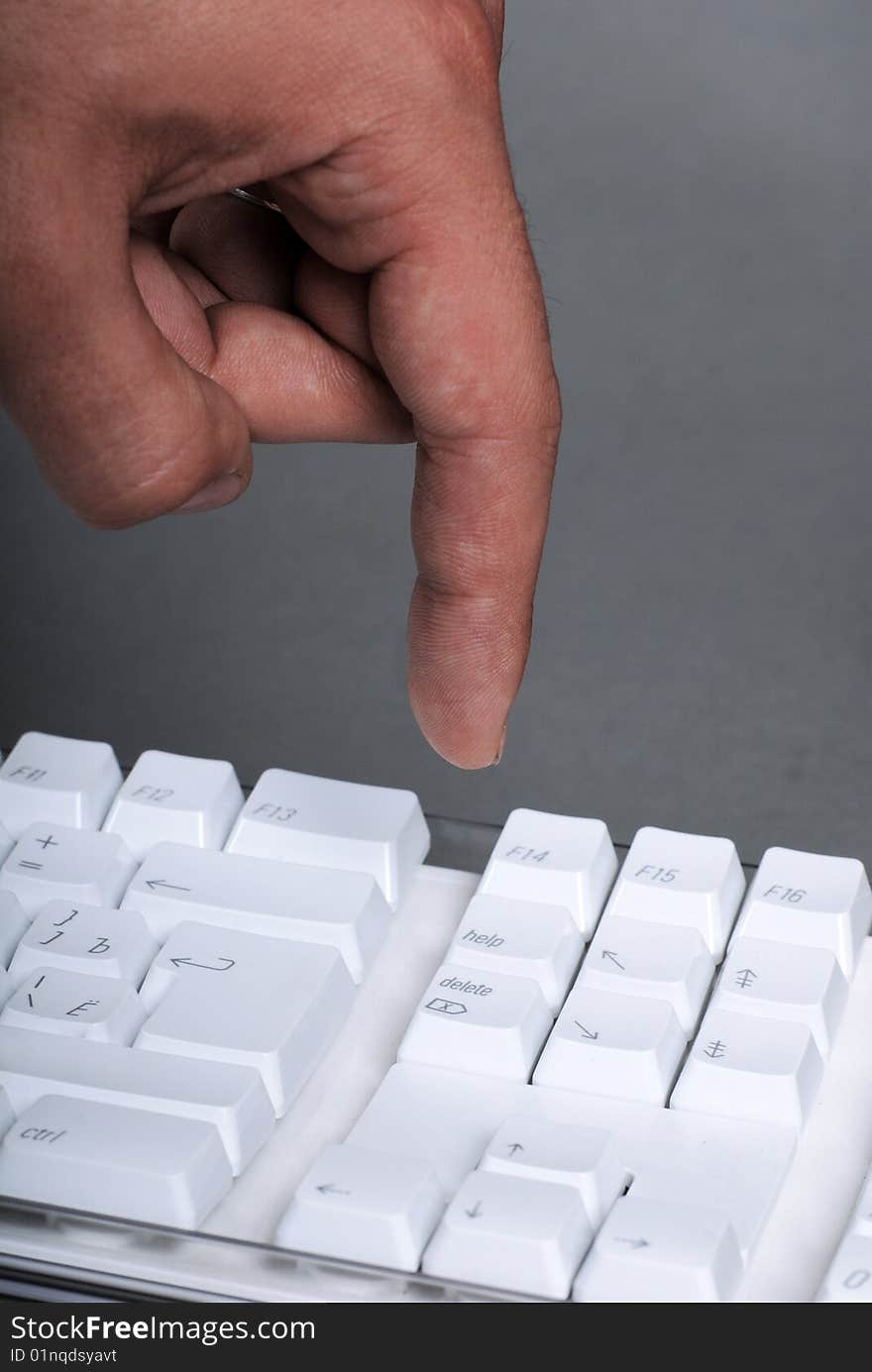 Vertical image of male hand on the white keyboard of computer