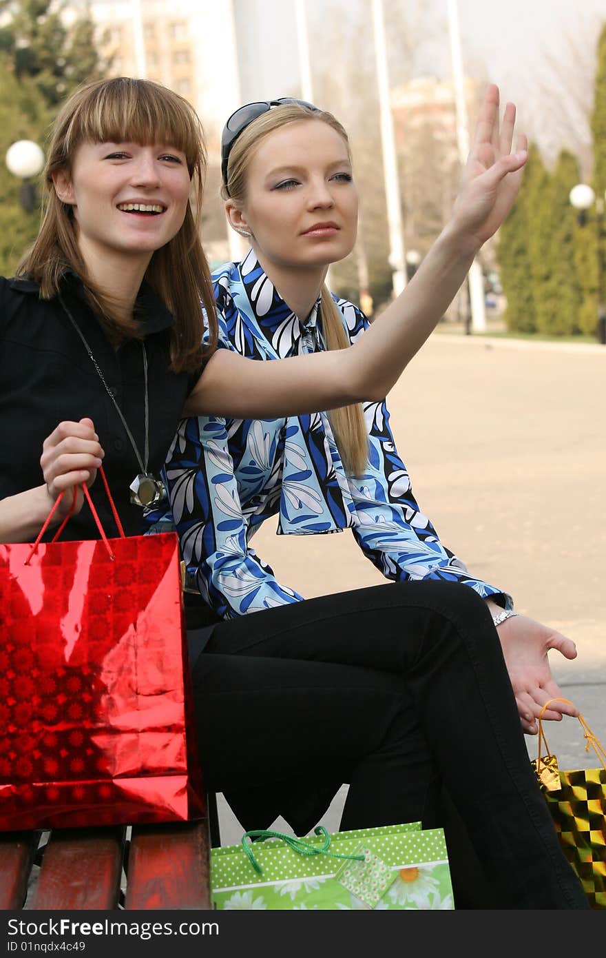 Two women on the bench waving somebody. Two women on the bench waving somebody