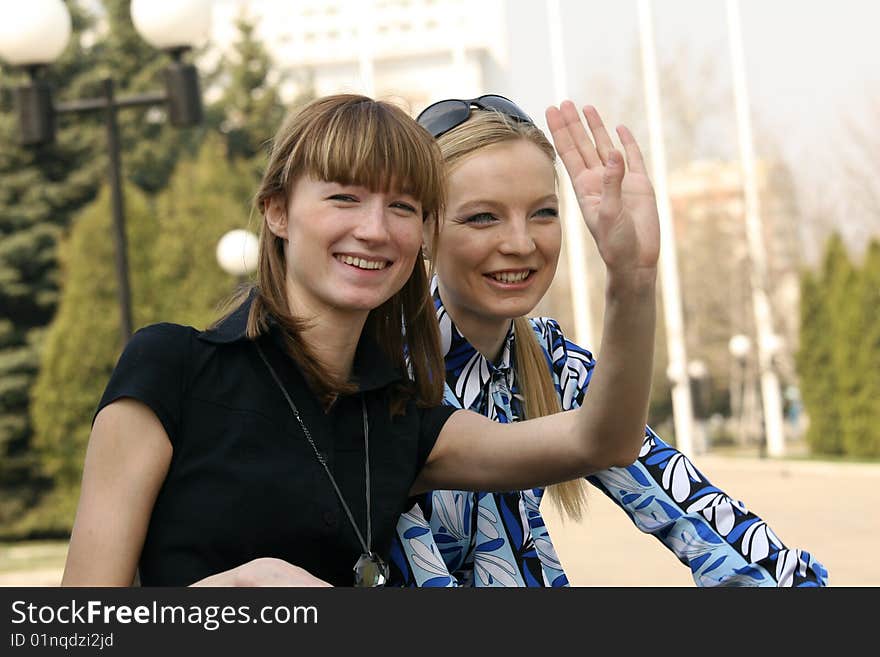 Women sitting on the bench and greet someone. Women sitting on the bench and greet someone