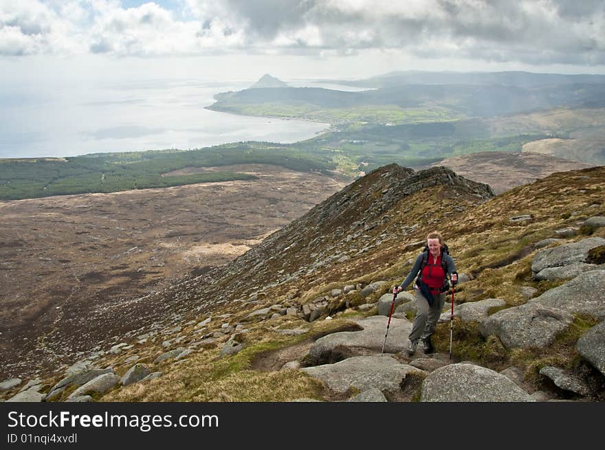 Woman walker with trekking poles on path in the mountains. Woman walker with trekking poles on path in the mountains