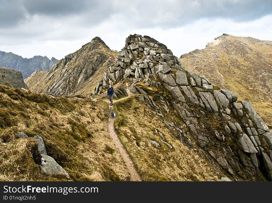 Woman walker with trekking poles on path in the mountains. Woman walker with trekking poles on path in the mountains