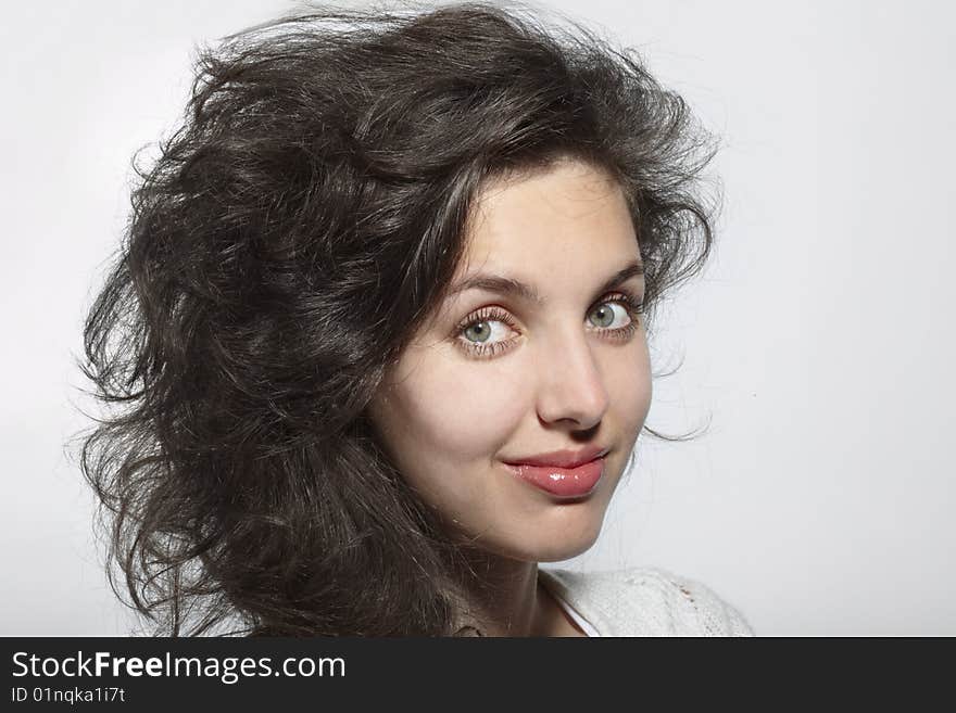 Portrait of the smiling dark-haired girl on a grey background