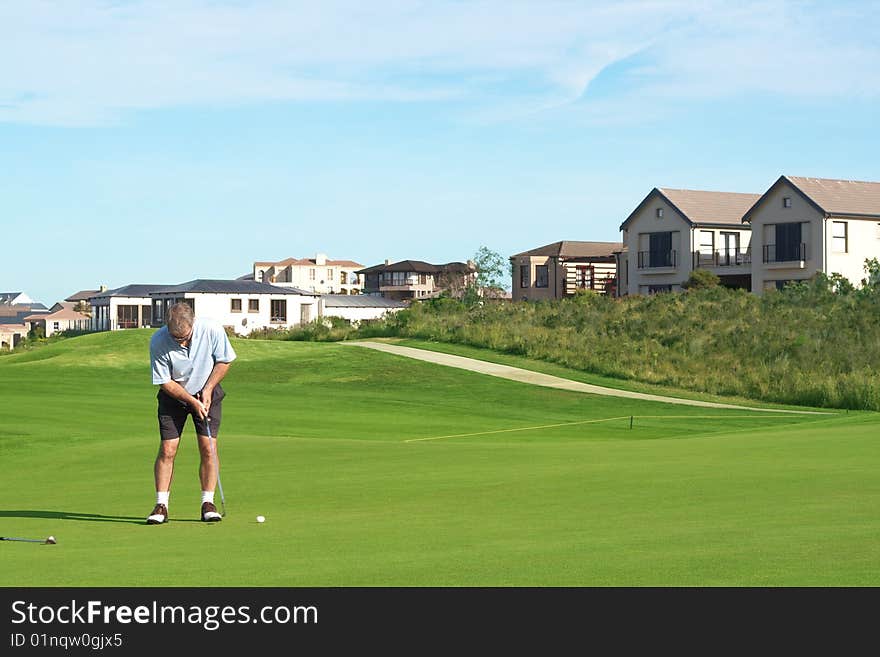 Senior male golfer playing golf on the green on a beautiful summer day. Senior male golfer playing golf on the green on a beautiful summer day