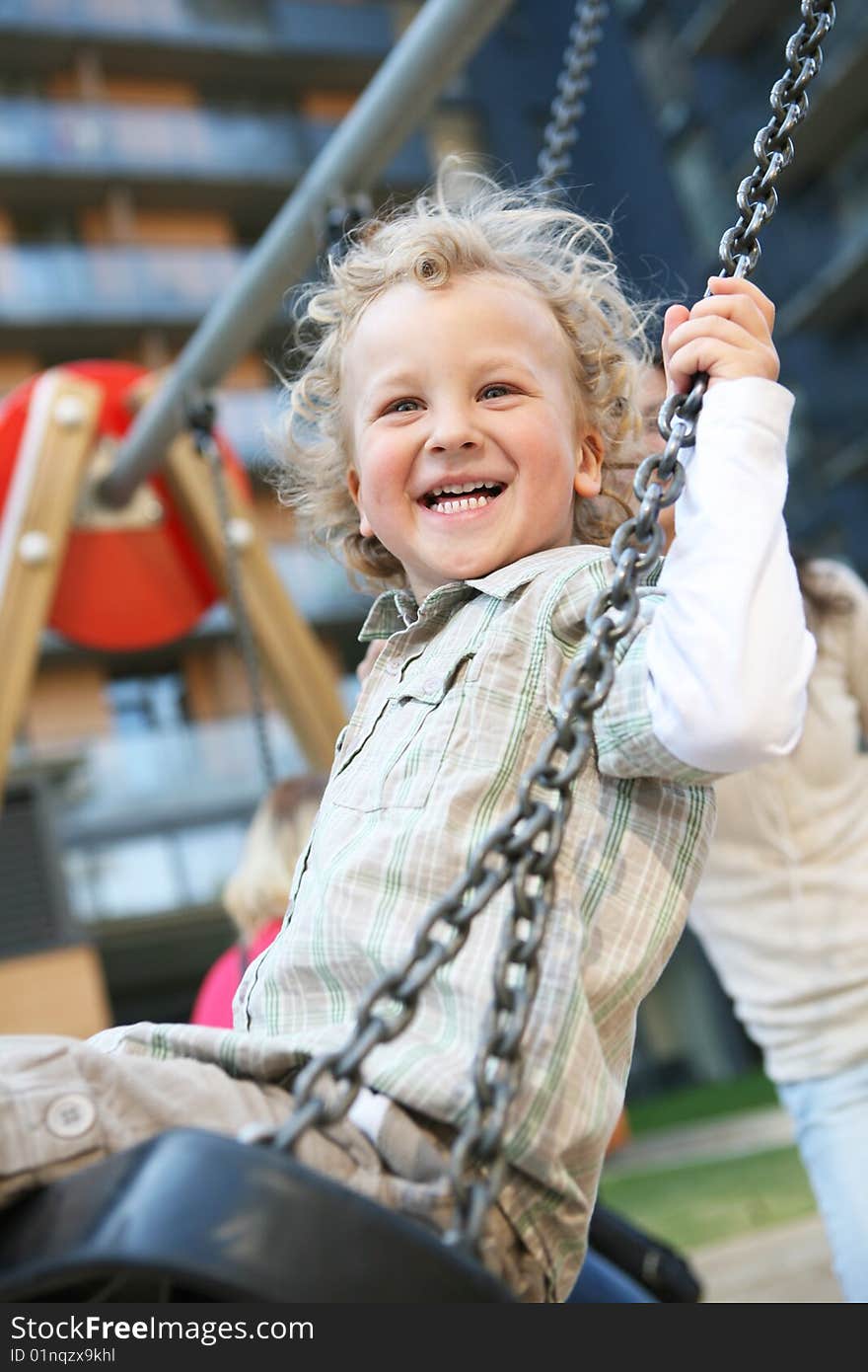 A little boy having a great time on a swing in a playground. A little boy having a great time on a swing in a playground.