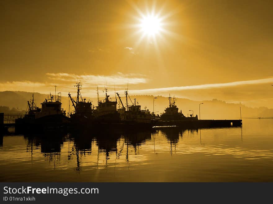 Sunset at the marina with boat silhouette and water reflection. Sunset at the marina with boat silhouette and water reflection