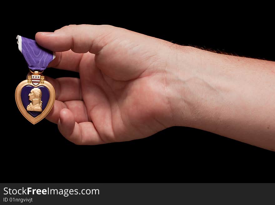 Man Holding Purple Heart War Medal on a Black Background.