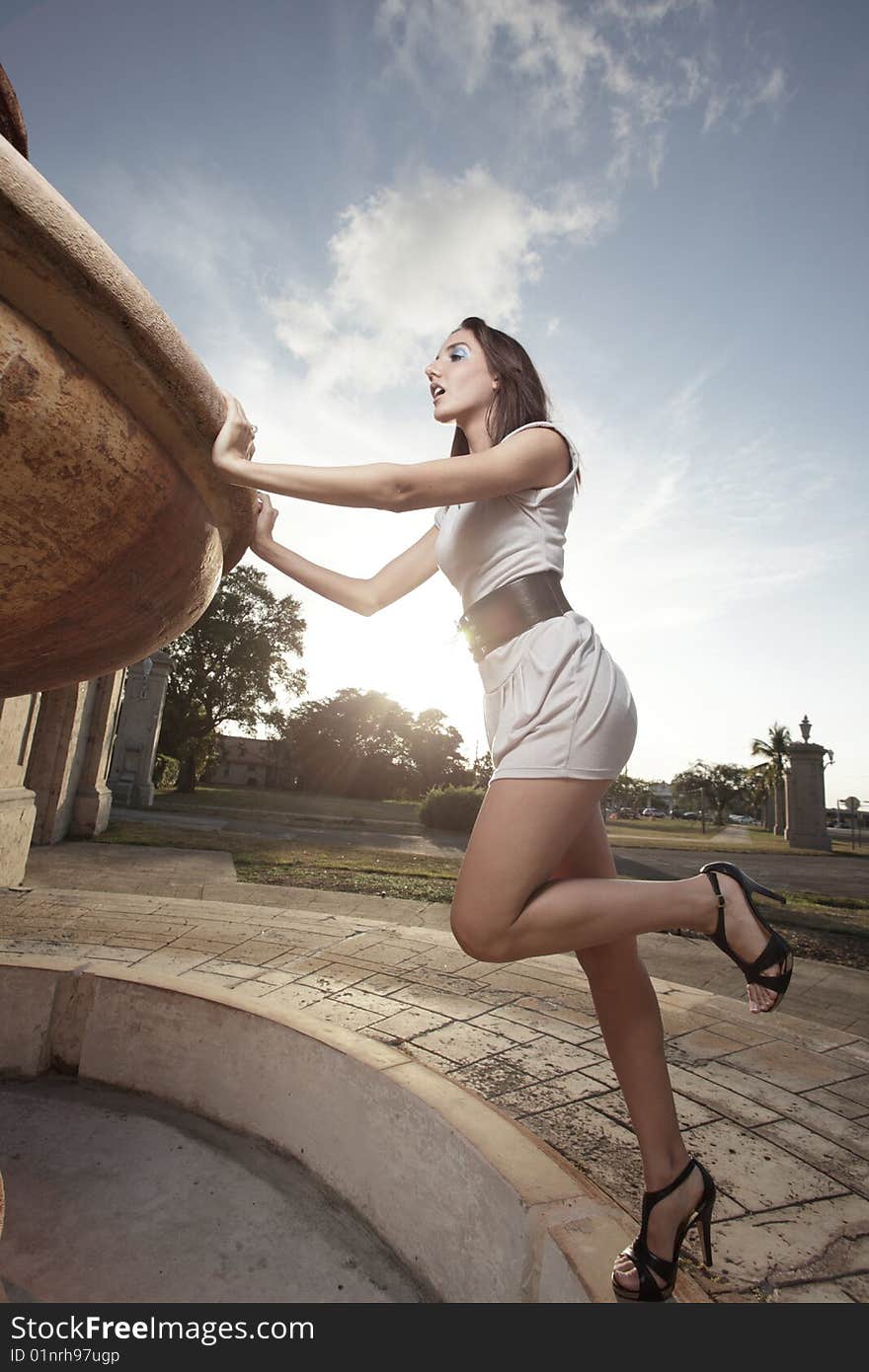 Young woman on her toes looking in a fountain. Young woman on her toes looking in a fountain