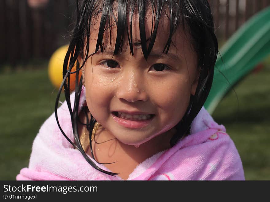 Little Asian Chinese Girl Dripping with water with a smile and a towel around her. Little Asian Chinese Girl Dripping with water with a smile and a towel around her