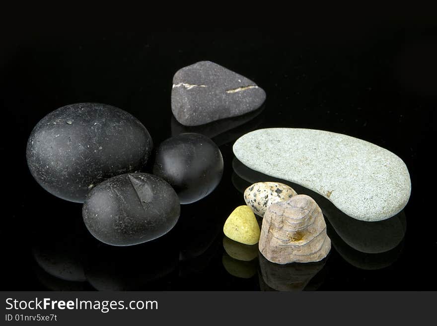 A collection of different shape, natural stones on top of a glass with reflection