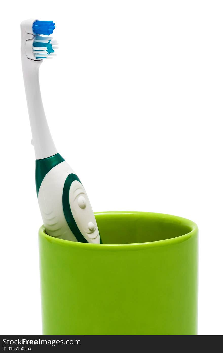 Toothbrush in a green glass on a white background