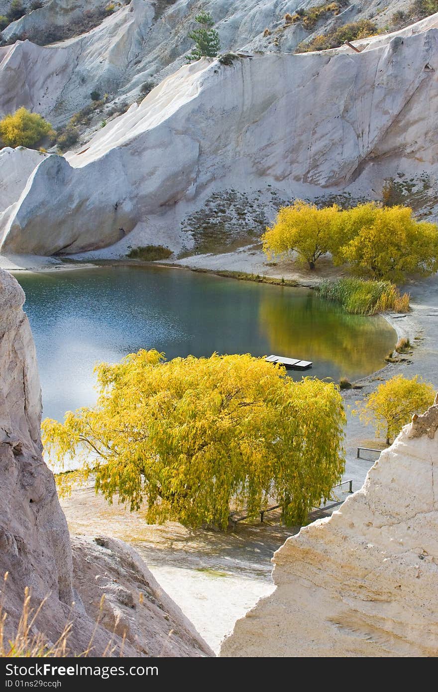 Golden autumn trees by lake with limestone cliffs at st bathans, south island, new zealand. Golden autumn trees by lake with limestone cliffs at st bathans, south island, new zealand