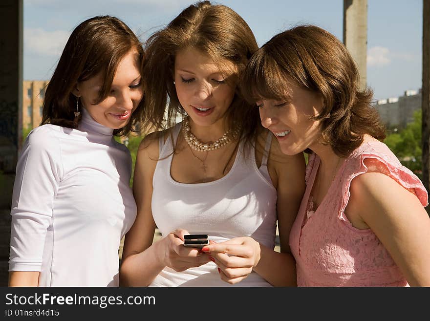 Portrait of three beautiful girls playing around with a mobile phone. Portrait of three beautiful girls playing around with a mobile phone