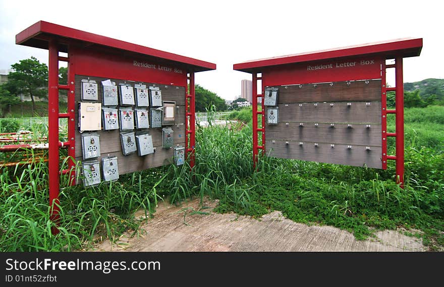 Metal mail boxes hanging on two red stands.