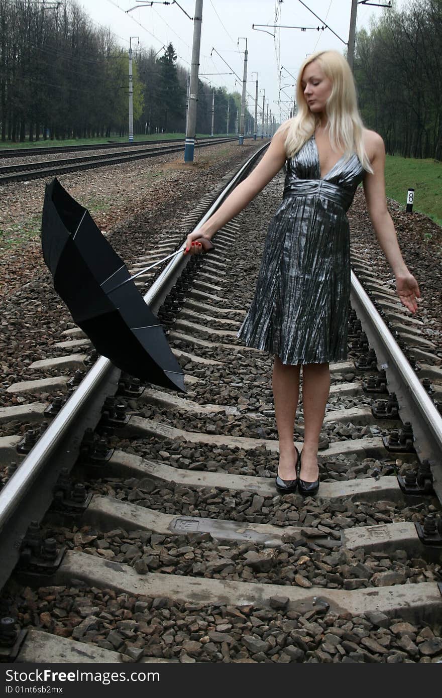 Girl with an umbrella standing on railroad