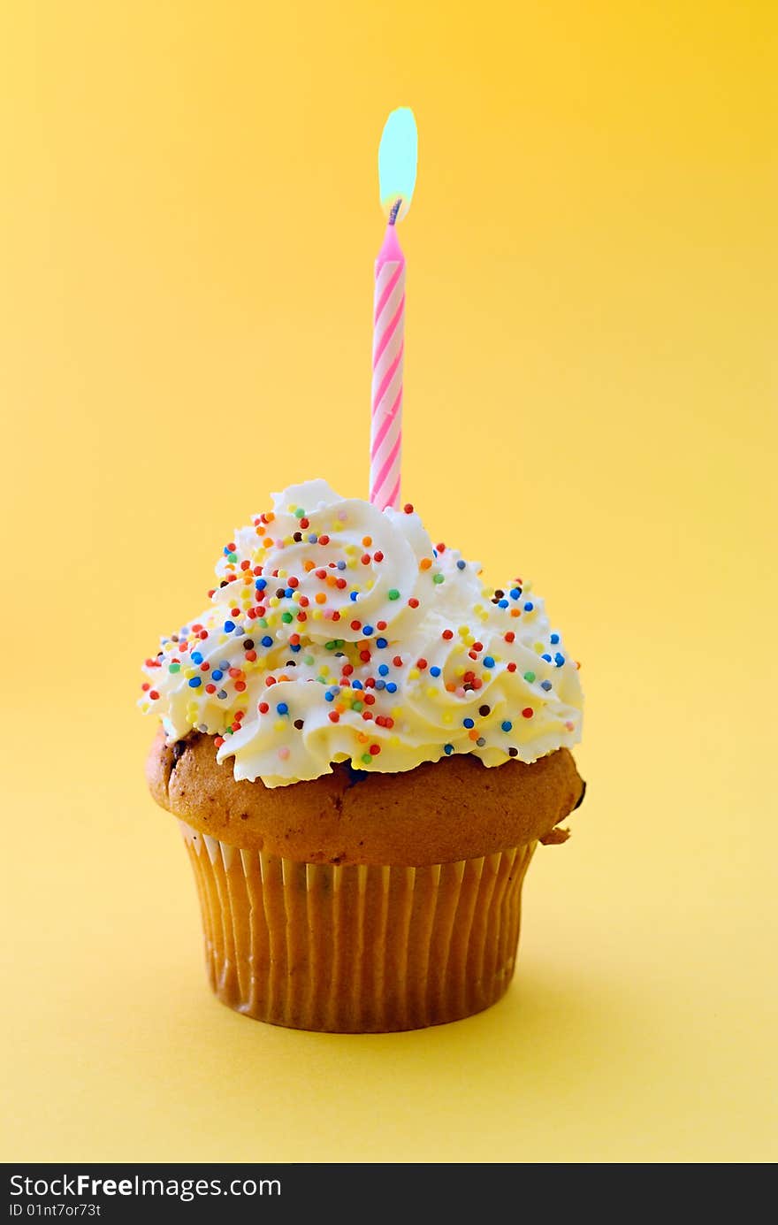 Muffin and candle isolated on yellow background