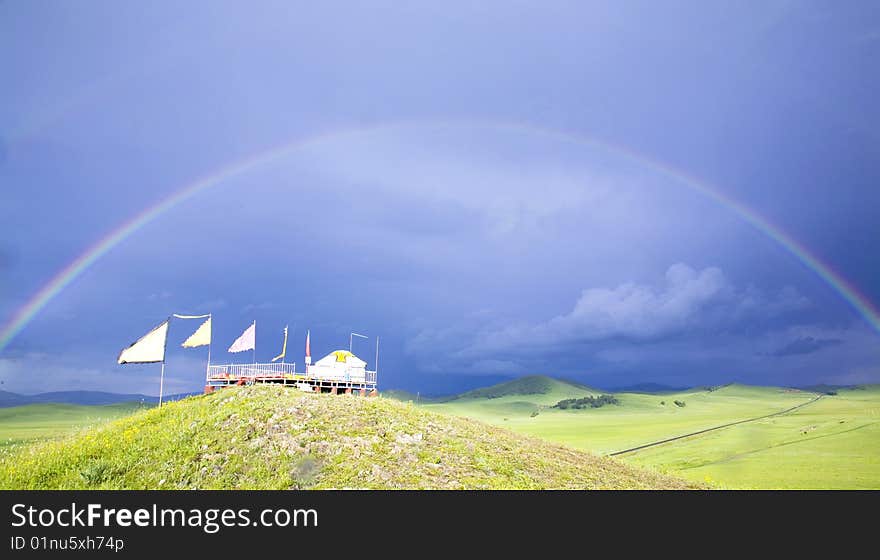 A rainbow arched across the sky and grassland. A rainbow arched across the sky and grassland