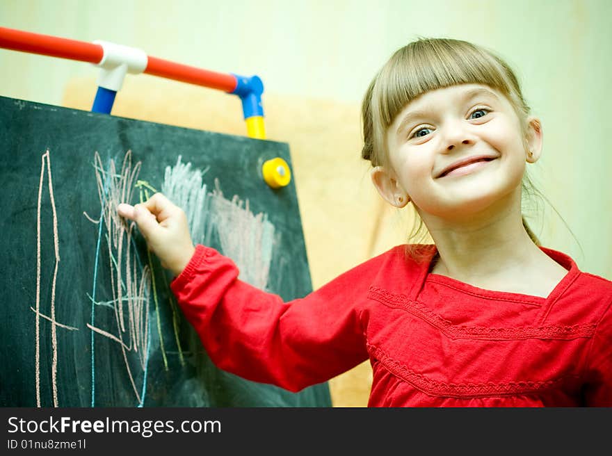 Girl draws with chalk on the blackboard