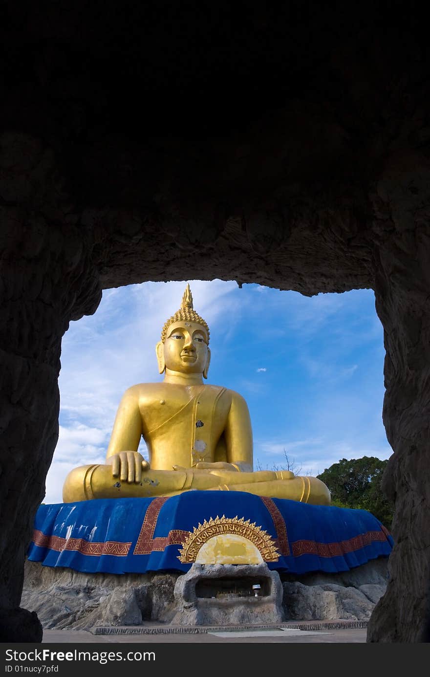 A large gold Buddha statue viewed from a cave. A large gold Buddha statue viewed from a cave