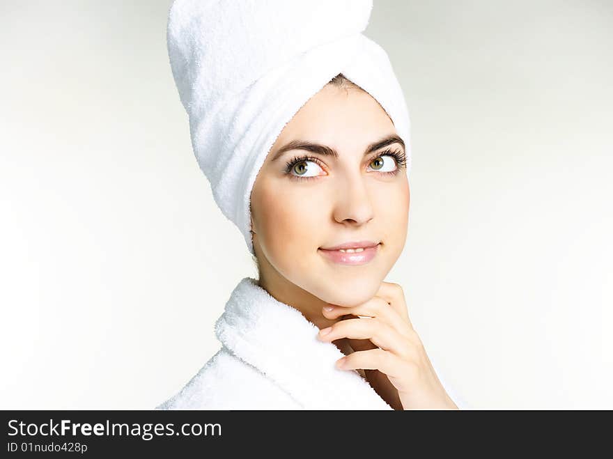 Portrait of a pretty girl wrapped into the white towel and wearing a white dressing gown